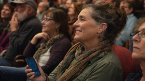 Woman wearing a modern hearing aid in a community venue while learning about Auracast broadcast audio