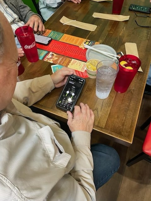 Patient using a smartphone hearing aid app during an Experience Hearing restaurant visit